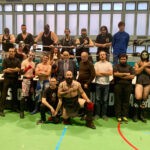 A wrestling association posing for a picture in a wrestling ring.